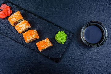 Sushi roll philadelphia with salmon, rice, cheese, cucumber, avocado and caviar on a slate board. Japanese food. Top view