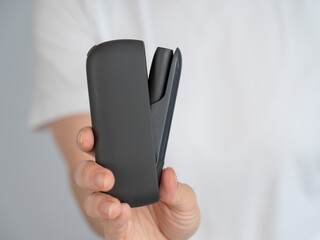 A woman takes a tobacco heating system out of a charger. Electronic cigarette.