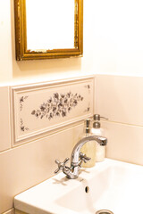 faucet and washbasin in a bright Provence style bathroom and a vintage mirror with cracks