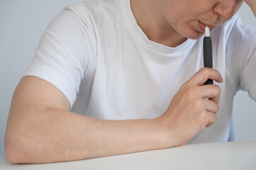 Tired woman smoking an electronic cigarette while working on a laptop. Tobacco heating system.