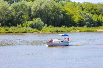 Recreational boat navigates through peaceful river waters with dense green forest creating natural...
