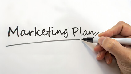 Hand underlining the words marketing plan on a whiteboard with a black marker isolated on white background