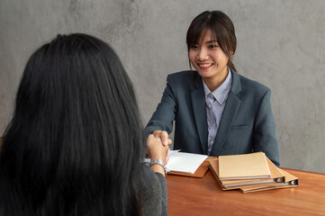 A professional business meeting between two women discussing opportunities and shaking hands with smiles.