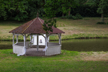 A quiet summer gazebo and a small boy sitting alone on a white bridge — concept of peaceful childhood and nature retreat.