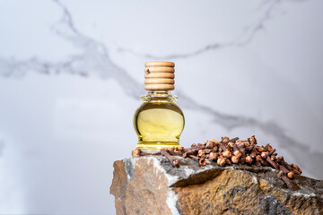 Clove essential oil in a bottle and dry cloves on a rustic wooden background.