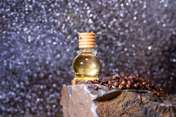Clove essential oil in a bottle and dry cloves on a rustic wooden background.