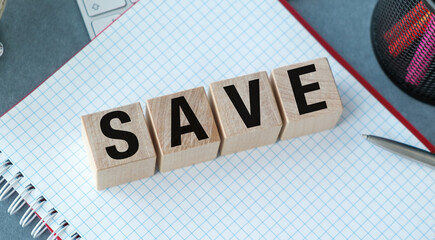 Save is written in wooden blocks on a blue and white sheet of paper