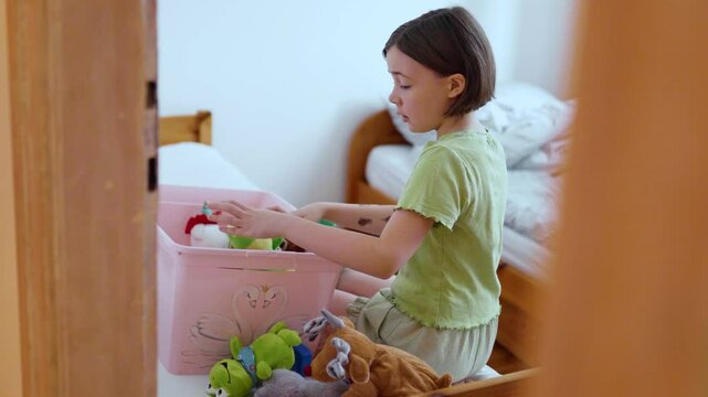 Child cleans up her toys.