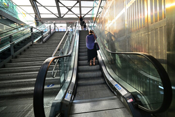 backview of alone woman on escalator at train station