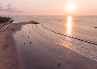 Sunset Beach in Bali, Indonesia. Badung City. Ocean Water and Tourists in Background