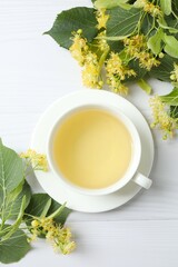 Green tea with fragrant linden in white cup on light background