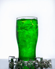 transparent glass of green lemonade with ice on light background