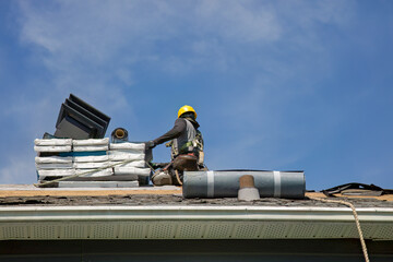 Professional Roofer in Hard Hat Installing Asphalt Shingles on Residential House Roof