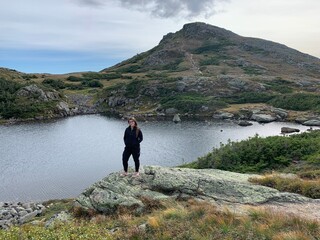 Hiker woman standing on rock near lake with mountain in the background