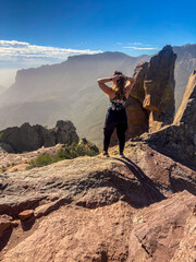 Woman standing on top of mountain overlooking desert valley 