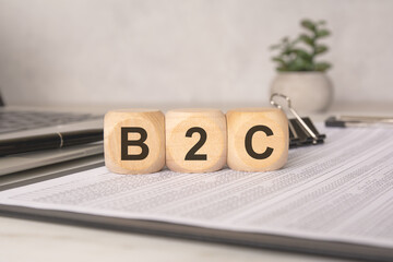 Wooden blocks with B2C letters on financial papers with laptop and office supplies
