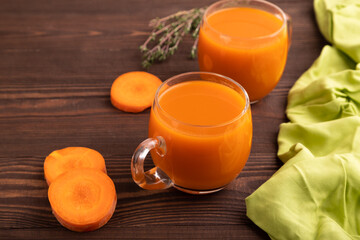 Two glasses with carrot juice, on wooden background and green textile. Diet, healthy eating. side view, close up
