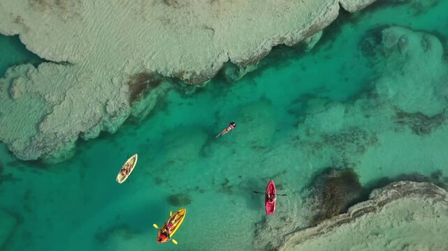 Aerial view of a woman floating in turquoise water and people kayaking in Sian Ka'an biosphere reserve, Mexico. Speed ramp effect