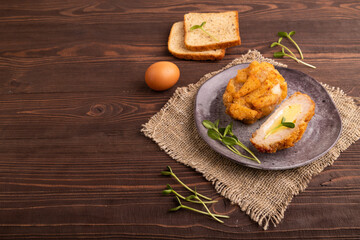 Chicken Schnitzel on gray plate with microgreen on brown wooden background and linen textile. side view, copy space