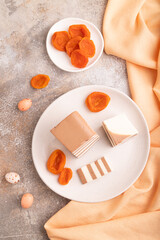 Cocoa and milk jelly with dried apricots on brown concrete background, top view, close up