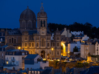 Vista nocturna del pueblo de Granville, con edificios iluminados y torres con campanarios en Normandia viajando por la costa de Francia en verano de 2021