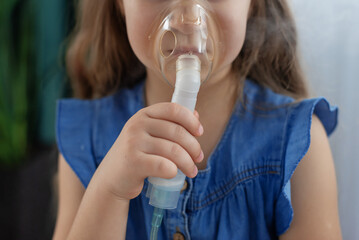 Young caucasian girl using nebulizer for respiratory treatment. Nebulizer use for children. Wheezy...