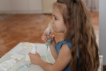 Young caucasian girl using nebulizer for respiratory treatment indoors. Wheezy Breathing