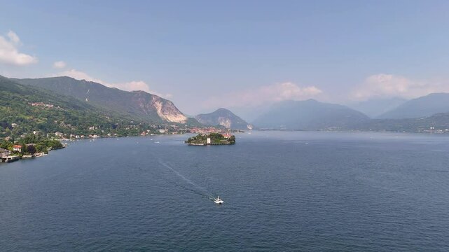 Drone video of a white private yacht sailing across Lake Maggiore from lush Isola Bella, Italy. Elegant luxury journey through iconic Northern Italy&rsquo;s scenic waterscape
