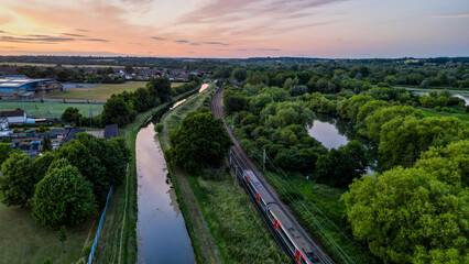 Aerial view of Hoddesdon, Hertfordshire showing river, sunset and housing estate with a train passing on the tracks