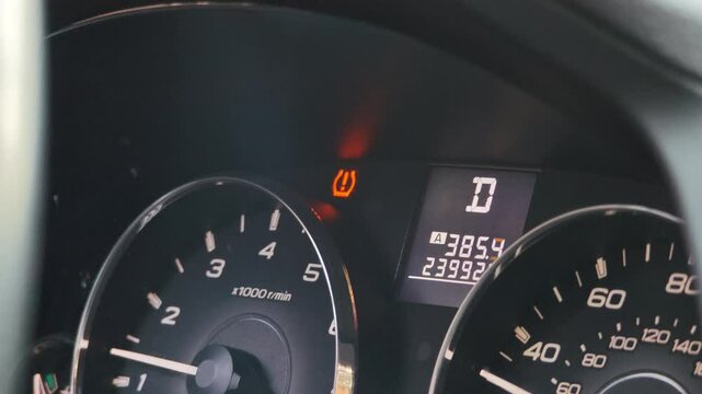 Closeup of car dashboard with illuminated brake warning light