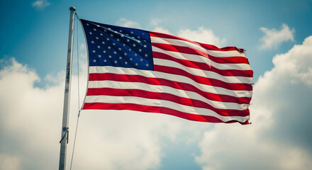A vibrant American flag proudly waves against a bright blue sky with white clouds, symbolizing patriotism, freedom, and national pride. Perfect for Fourth of July, Veterans Day, and US concepts