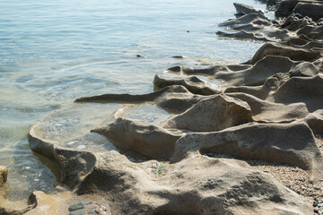 Beautiful eroded stone on calm sea waters on sunny summer day on the beach closeup