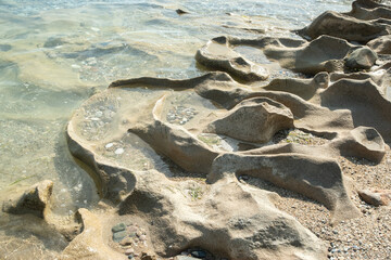 Beautiful eroded stone on calm sea waters on sunny summer day on the beach closeup
