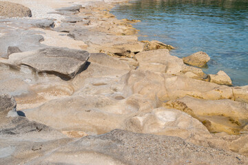 Beautiful eroded stone on calm sea waters on sunny summer day on the beach closeup