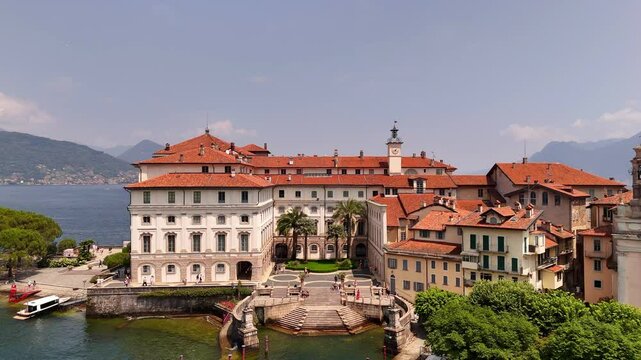 Drone video of Isola Bella&rsquo;s Borromeo Palace seen from the lake. Elegant red-roofed estate rises above the water, surrounded by Alpine peaks, lush gardens, and sparkling Lake Maggiore, Italy