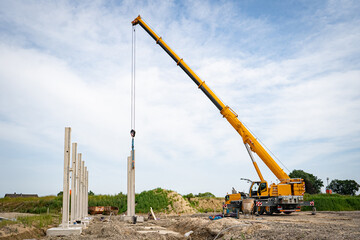 Aufstellen von großen Betonteilen mit einem Baukran für den Bau einer Industriehalle und...