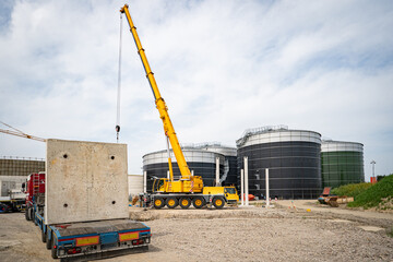 Aufstellen von großen Betonteilen mit einem Baukran für den Bau einer Industriehalle und Biogasanlage.