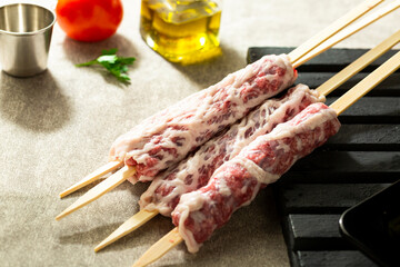 Raw lamb skewers ready for grilling, wrapped in lamb fat.