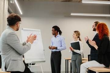 Diverse business team clapping after successful presentation in modern office
