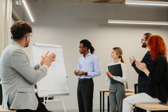 Diverse business team clapping after successful presentation in modern office - Powered by Adobe