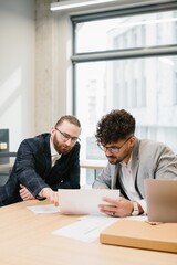 Obraz premium Businessmen working together analyzing financial documents in office