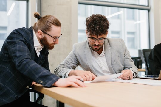 Two businessmen working together reviewing documents at office desk