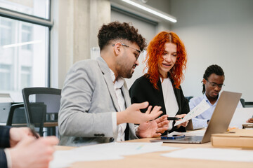 Business people working together in modern office analyzing charts on laptop