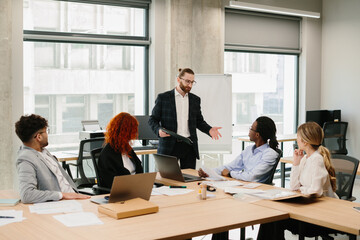 Businessman leading meeting with diverse team in modern office