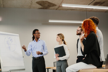 Businessman explaining pie chart during presentation to colleagues