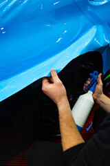 Detailing experts use hydration spray for controlled application of blue PPF film. Detailer uses...