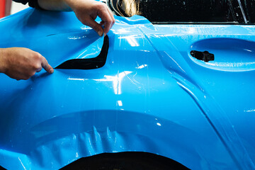 Cutting blue PPF with blade. Cutting blue paint protection film with blade during detailing job...