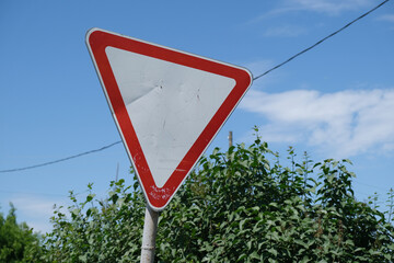 Give Way road sign against clear blue sky and trees, transportation, safety, traffic rules and...
