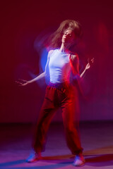 A young woman dances contemporary dances in blue and red light. Long exposure. Vertical photo. 
