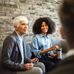 Two diverse colleagues on coffee break chatting with male colleague